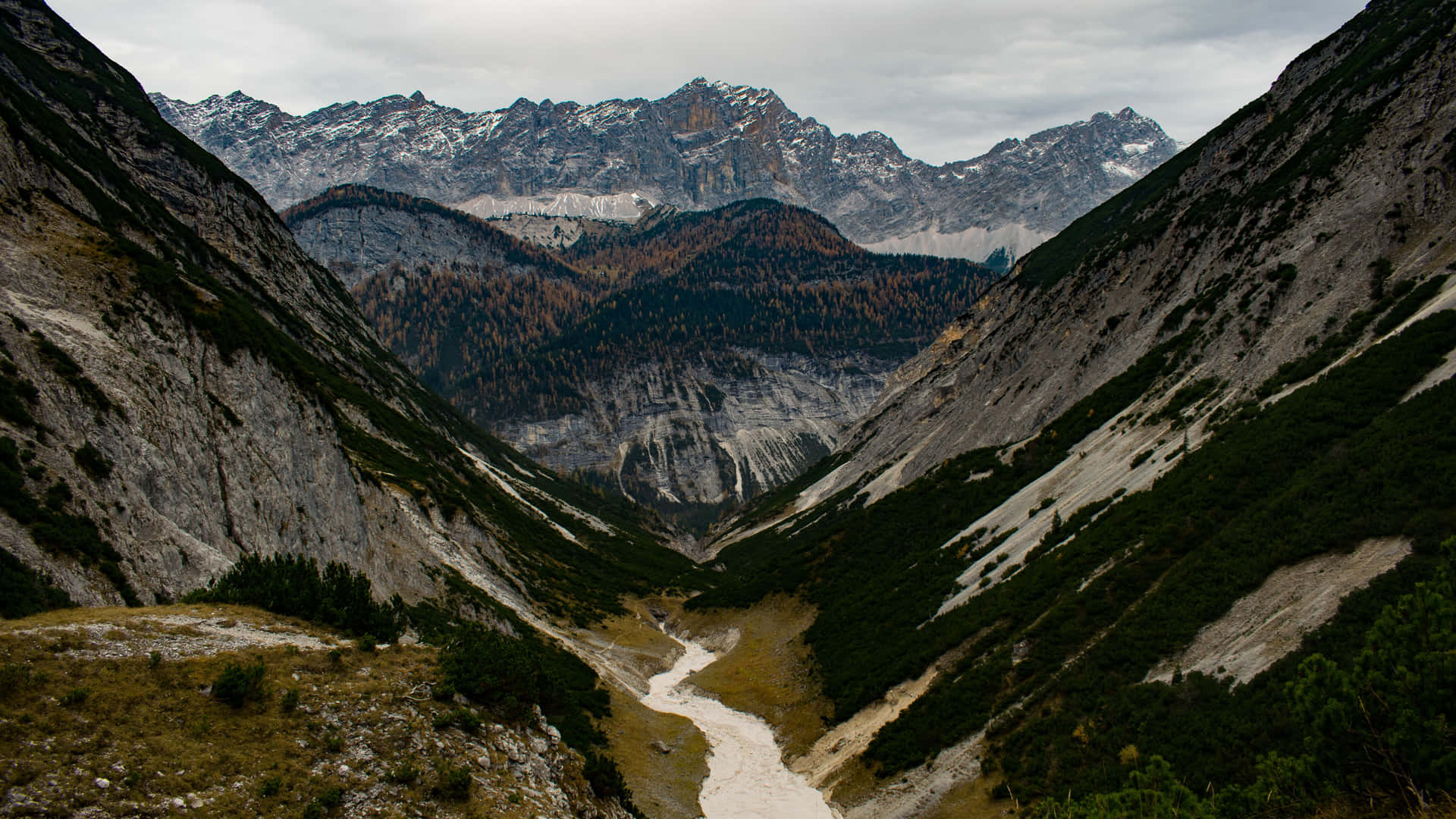 一條河流流經山谷，遠處有白雪覆蓋的山峰。