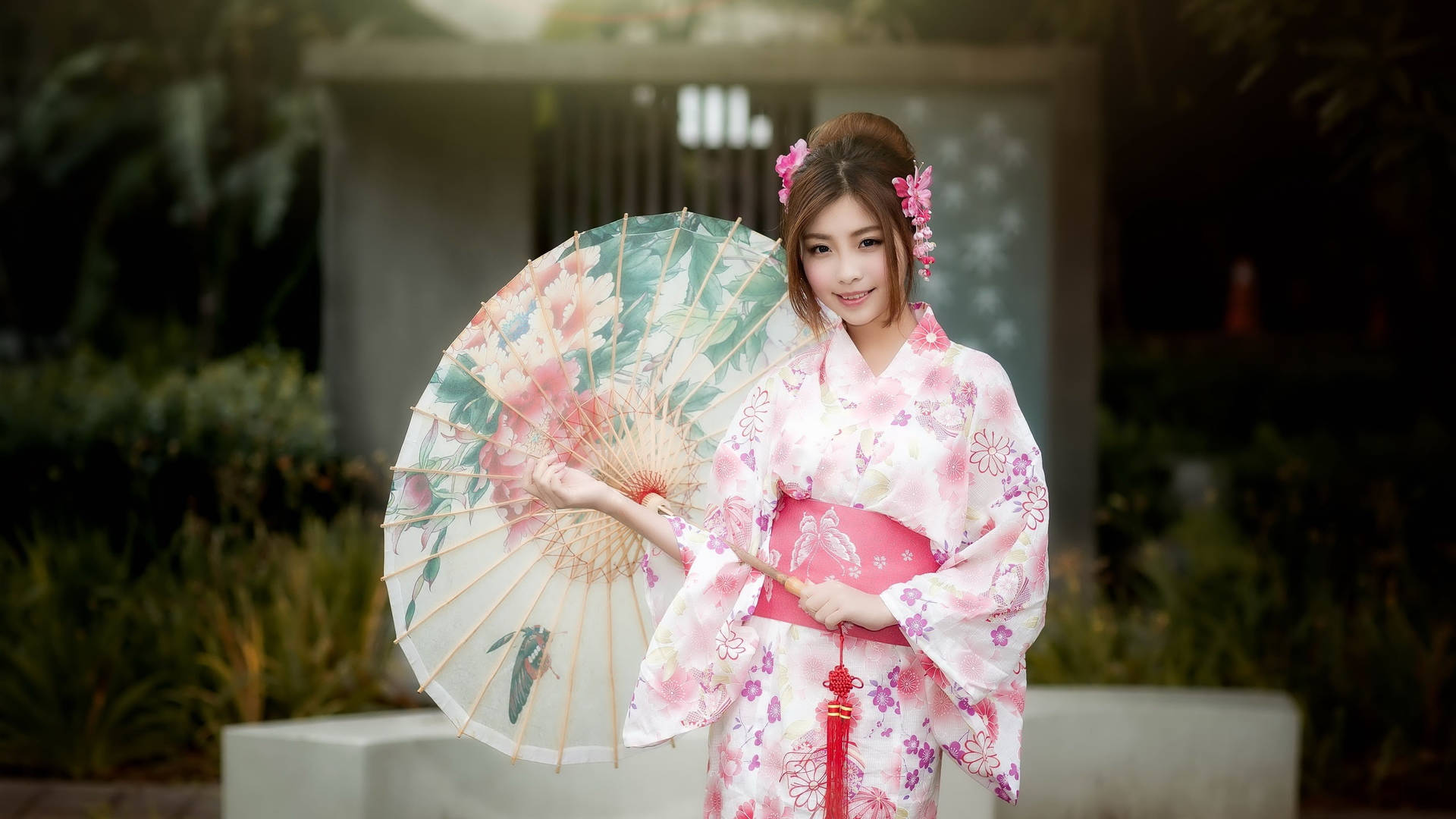 身穿粉色花卉和服的女性在花園中手持裝飾傘