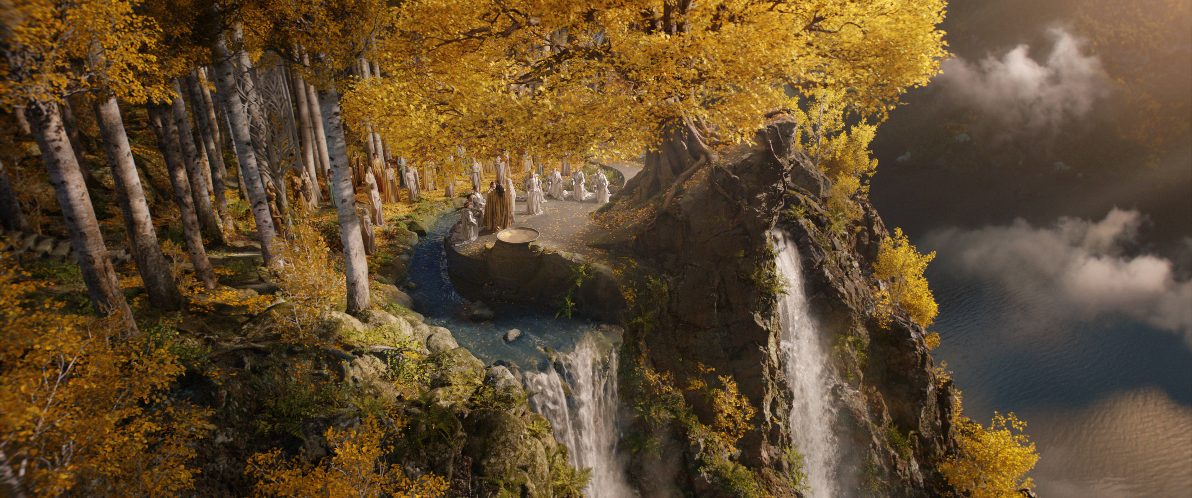 《指環王：力量之戒》中土大陸風景 壁紙 — 神秘嘅秋日森林，金色樹木俯瞰懸崖瀑布，流入下方迷霧大海。