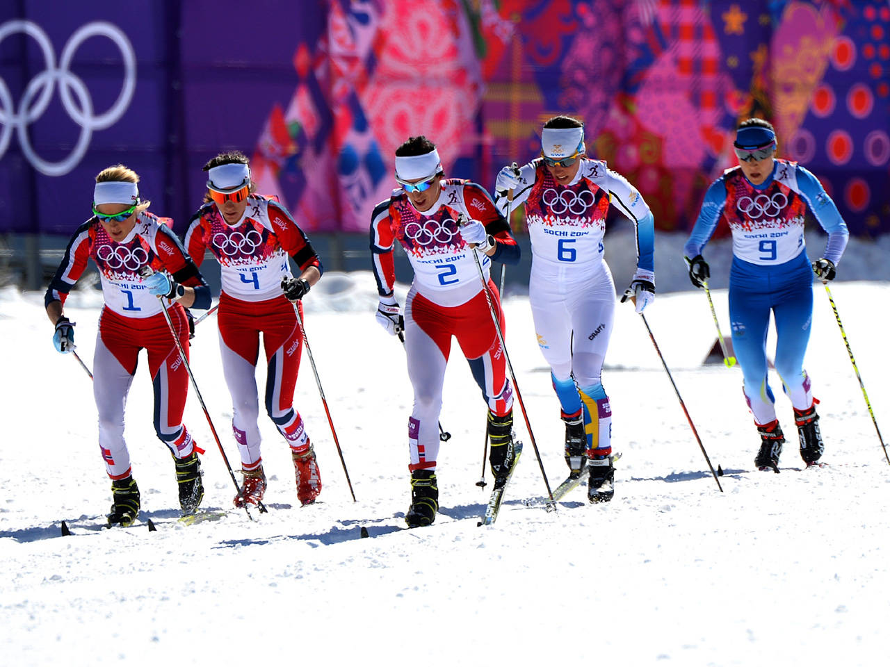 五名身穿奧運制服的女滑雪選手在雪道上。
