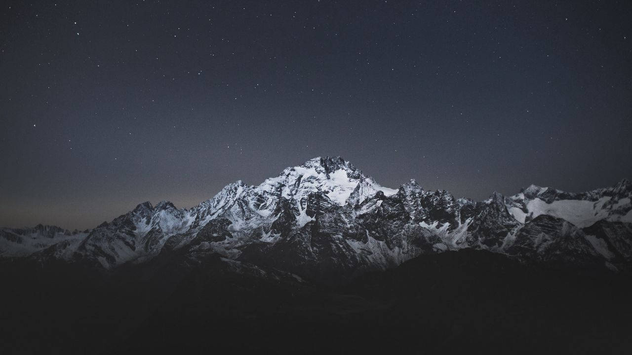 繁星夜空下帶有微弱極光的積雪山脈