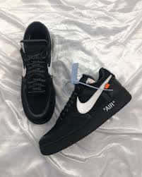 黑色Nike Air Force 1運動鞋，帶白色swoosh和橙色標籤，在銀色布料上。