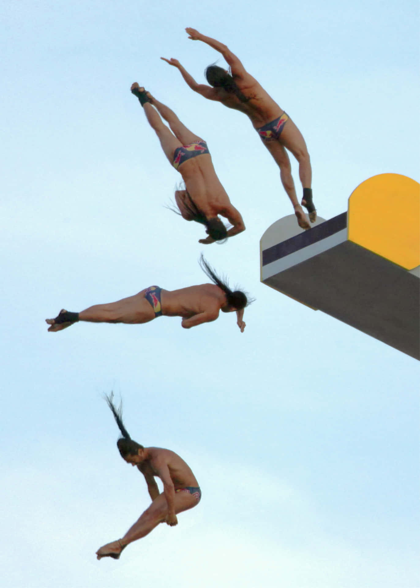 四位跳水運動員在空中進行同步跳水，背景是晴朗的天空。