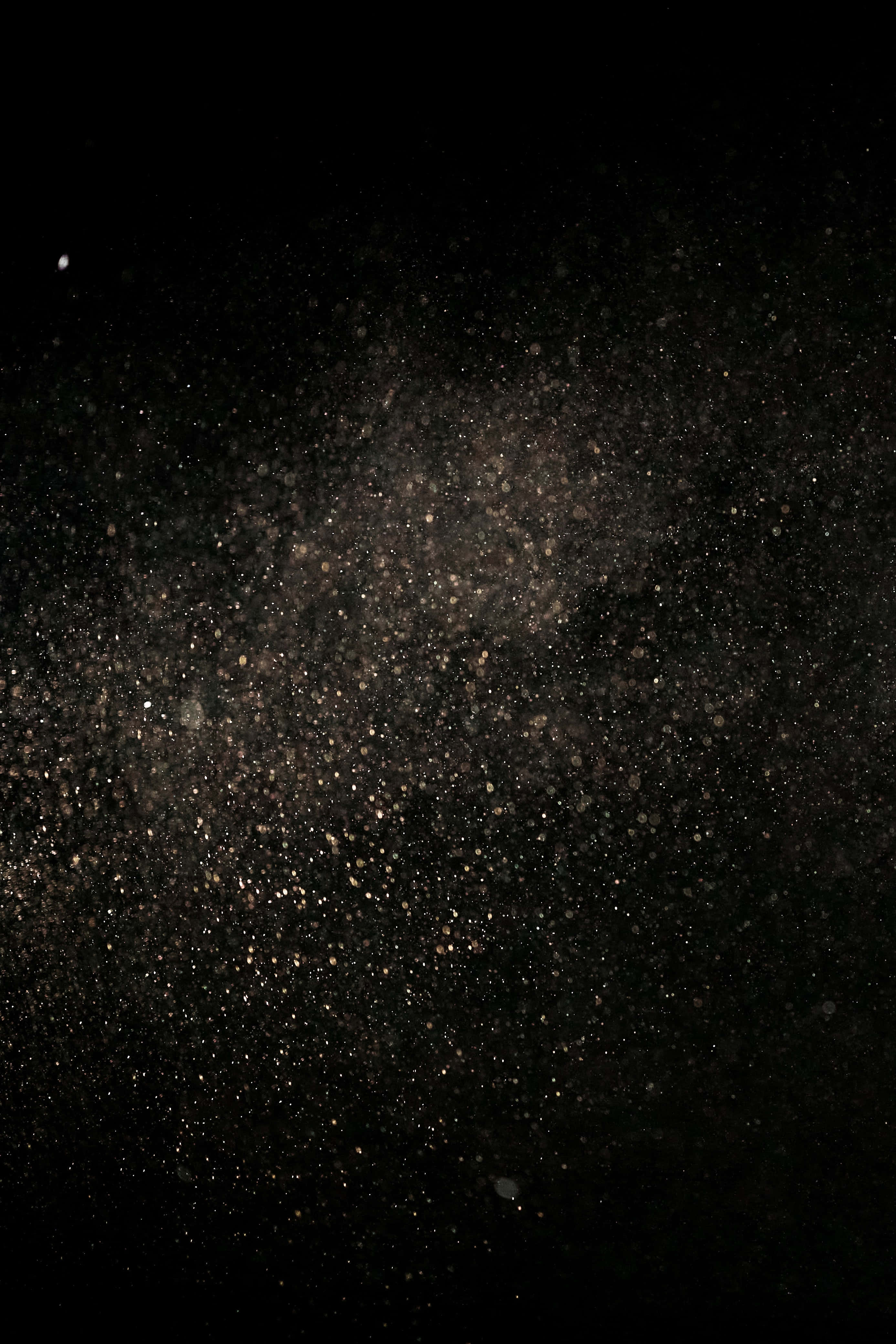 捕捉塵埃的美與神祕 壁紙 — 宇宙塵埃雲在深邃的黑色太空中旋轉，閃爍著金色粒子和微弱的星星。