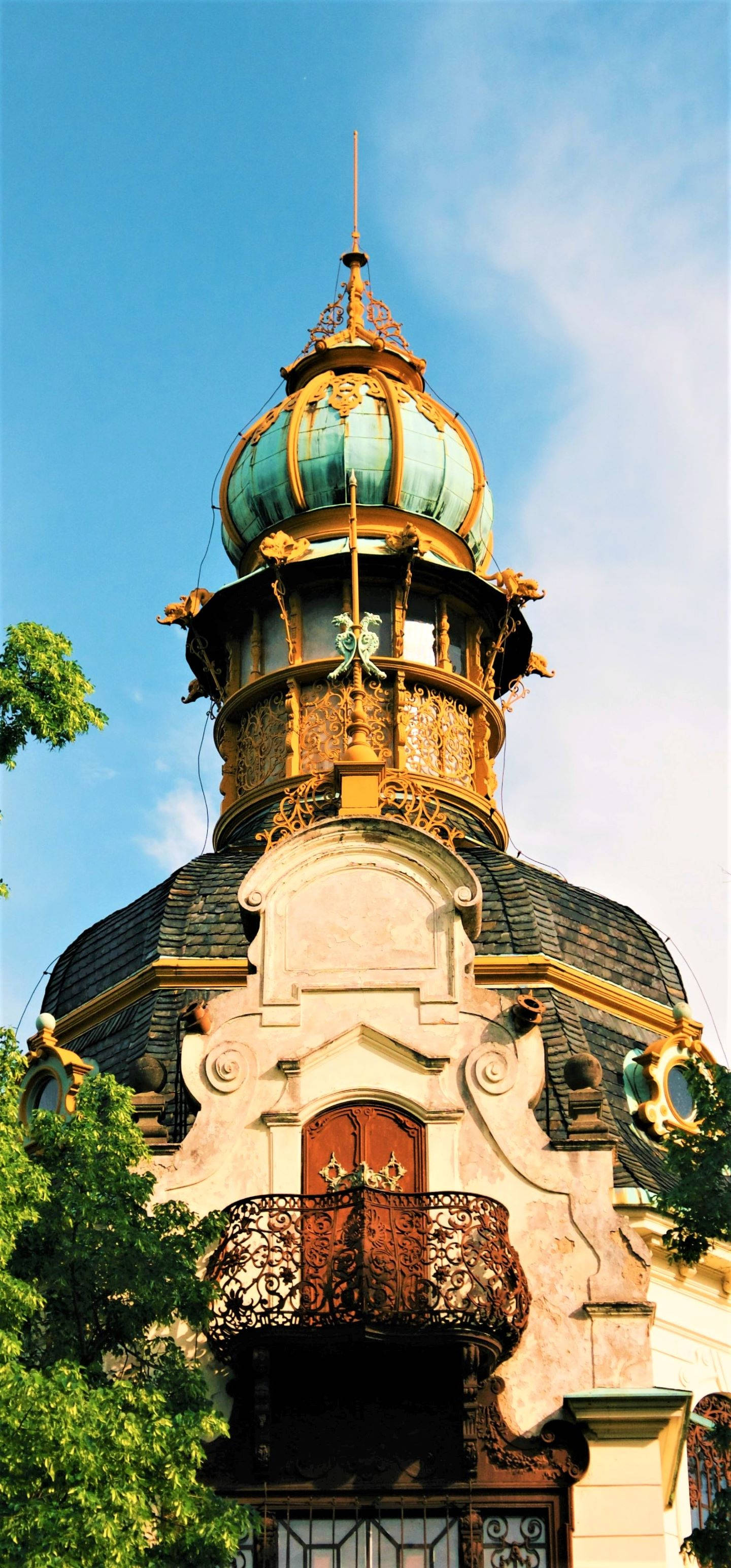 捷克共和國漢瑙花園 壁紙 — 一座令人驚嘆的新藝術風格建築，擁有綠松石色的圓頂和華麗的金色細節，背景是清澈的藍天。