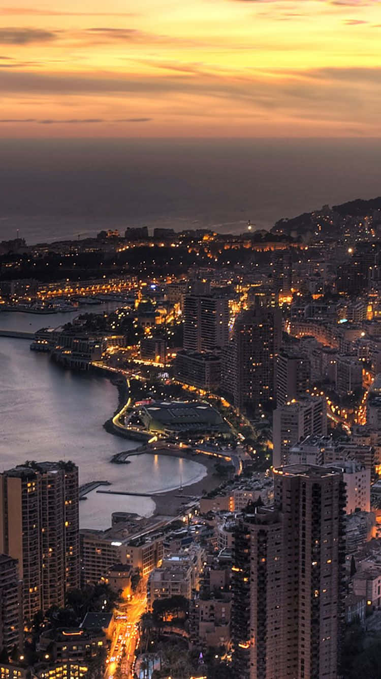 日落時分燈火通明的摩納哥沿海城市，金色天空和海景。