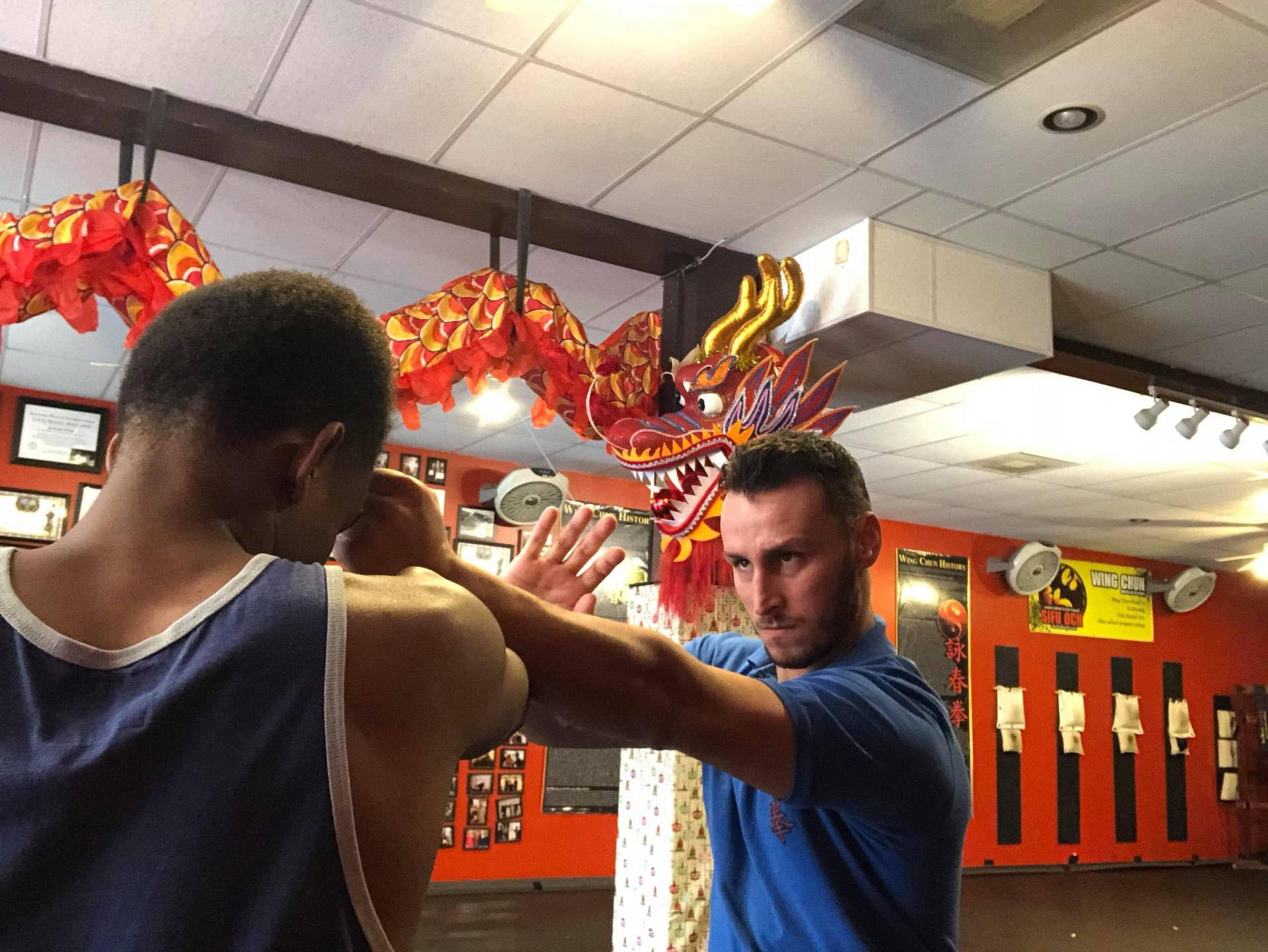 武術教練在有紅色龍裝飾的練習室中教導學生詠春拳。