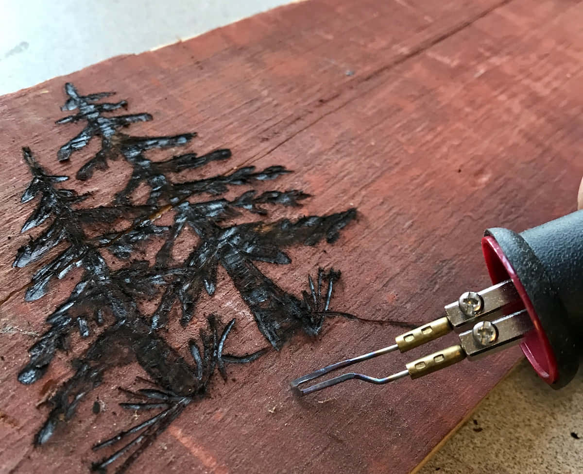 木燒工具在木頭上創建松樹圖案的近距離特寫。