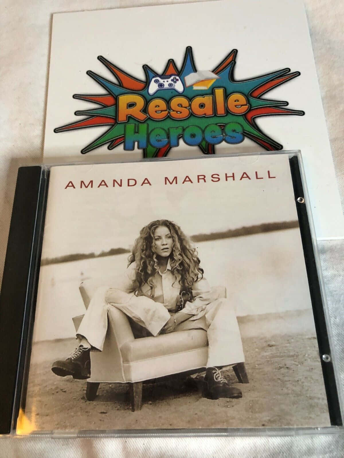 Amanda Marshall 的 CD 封面，帶有沙灘場景和 resale heroes 貼紙。