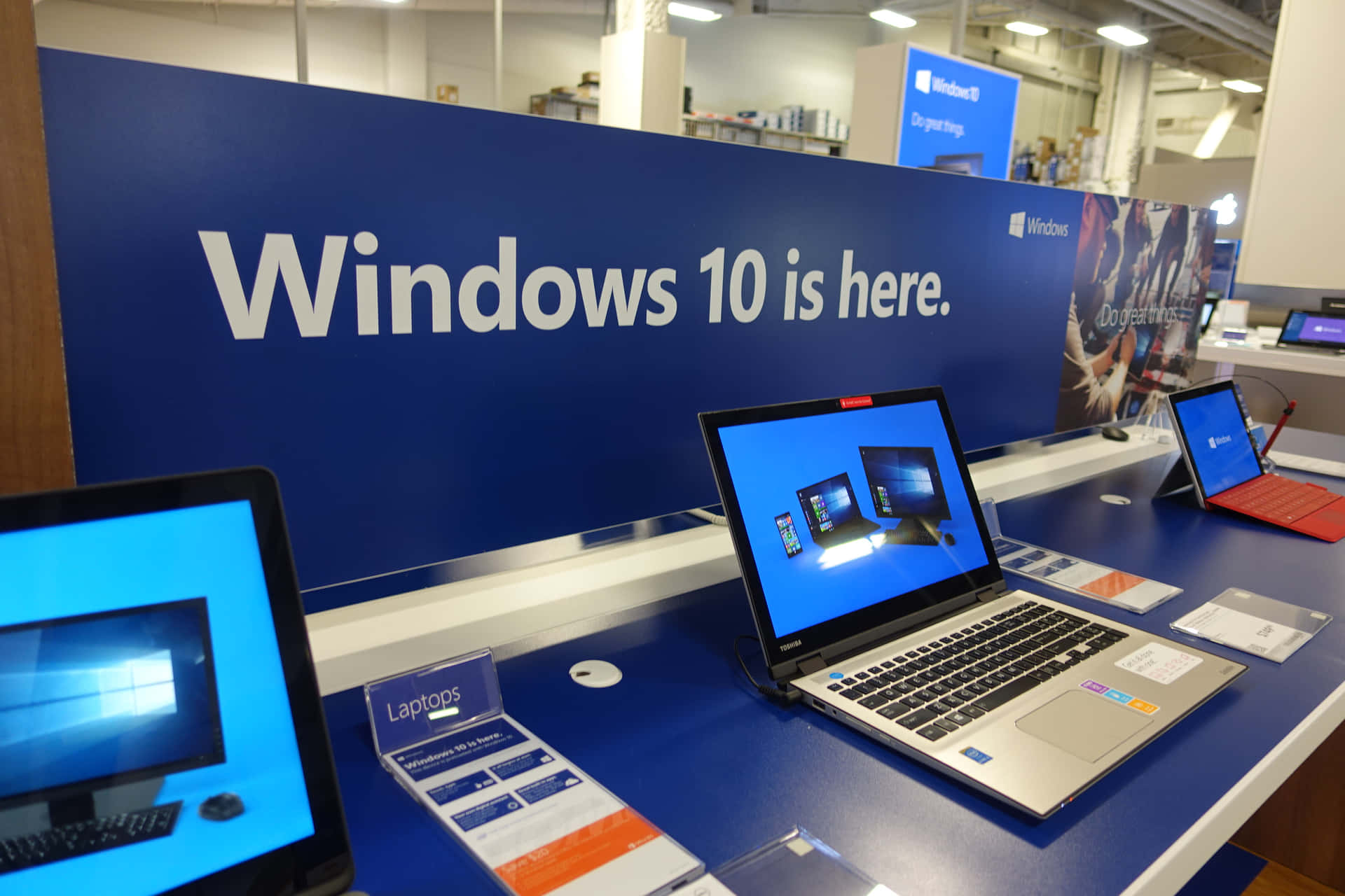 藍色展示架上的筆記型電腦，背景有Windows 10宣傳標誌。