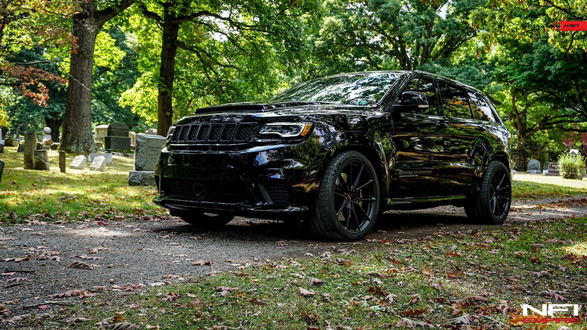 黑色Jeep Grand Cherokee SRT停泊在墓園中，伴有秋葉和墓碑。