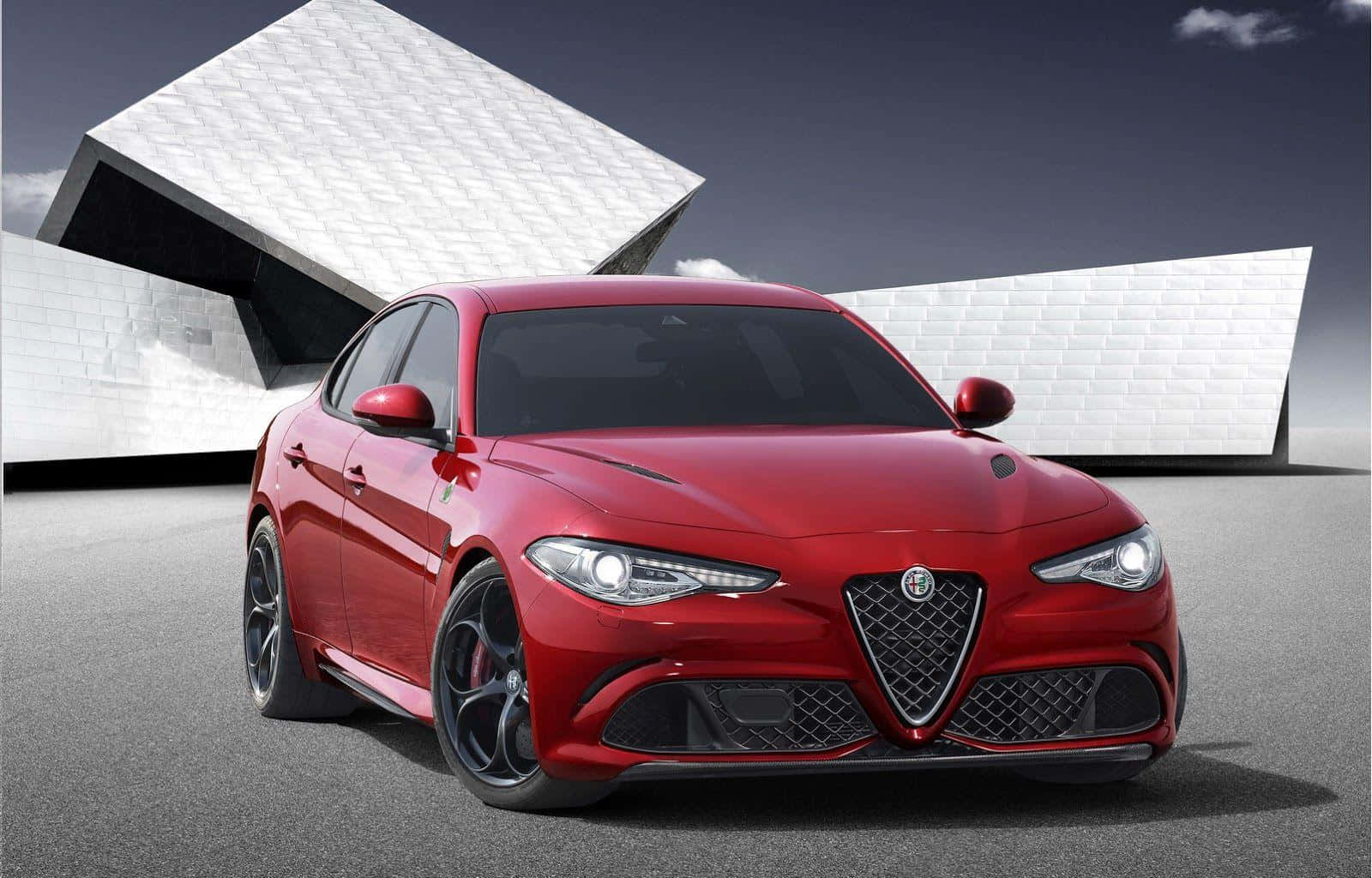 探索Alfa Romeo的力量 壁紙 — 一架亮紅色嘅Alfa Romeo跑車停泊喺一座純白色幾何建築前面，天色陰沉。