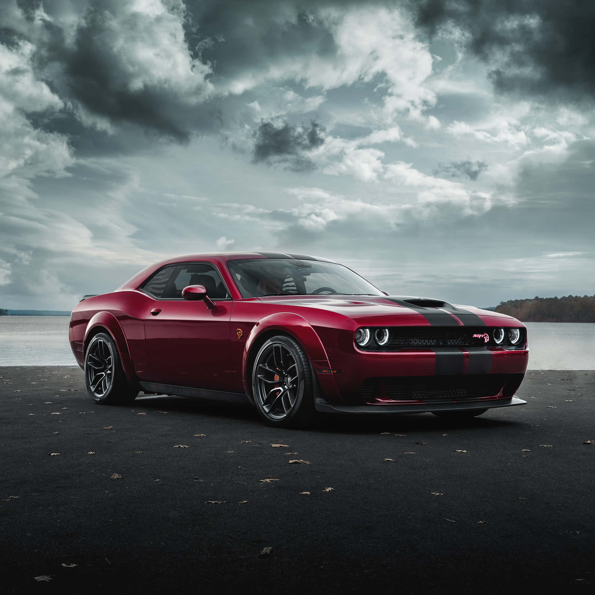 紅色Dodge Challenger SRT在暴風天空下停泊在近水處。