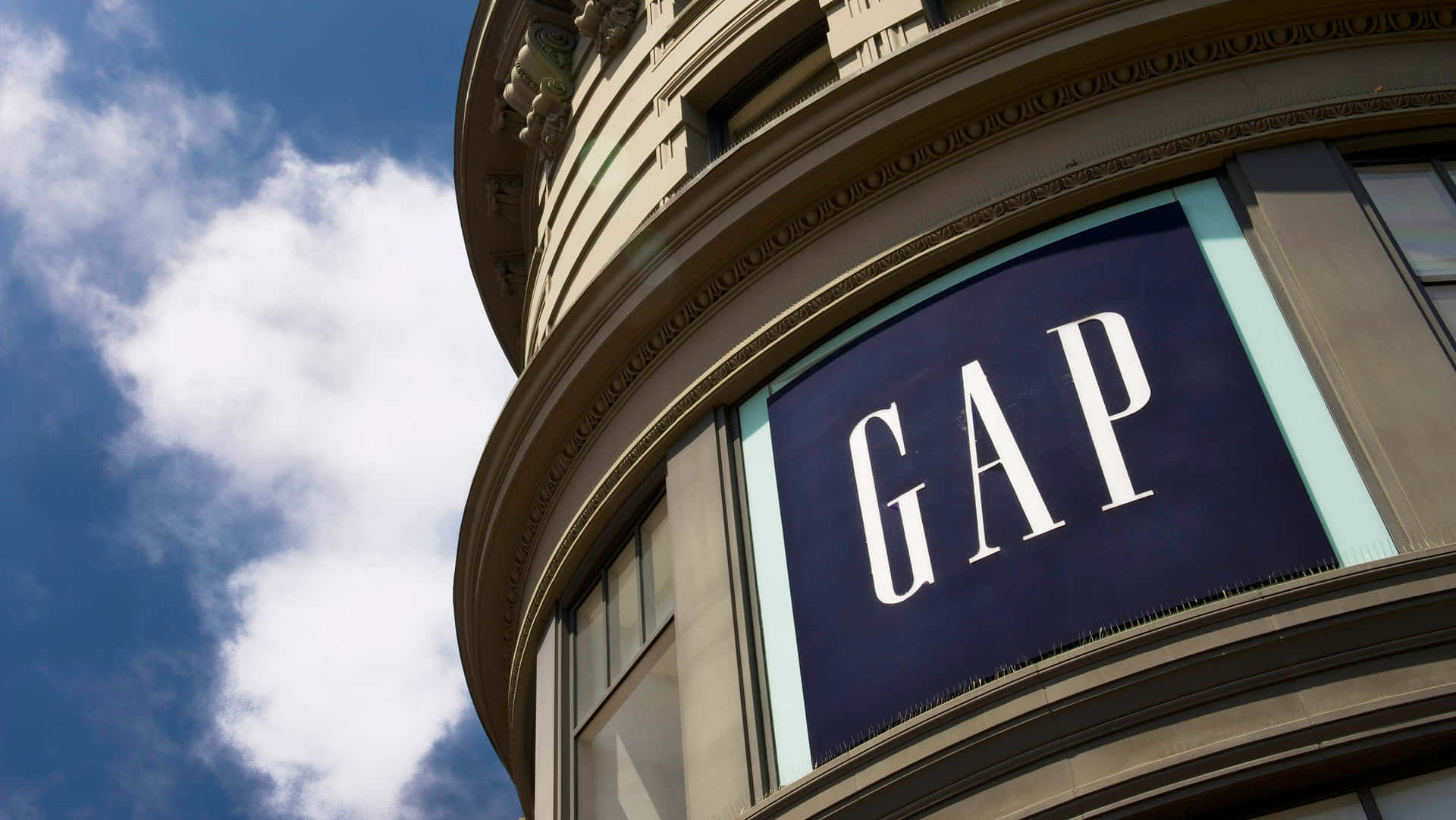 GAP商店招牌在弧形建築上，藍天白雲下