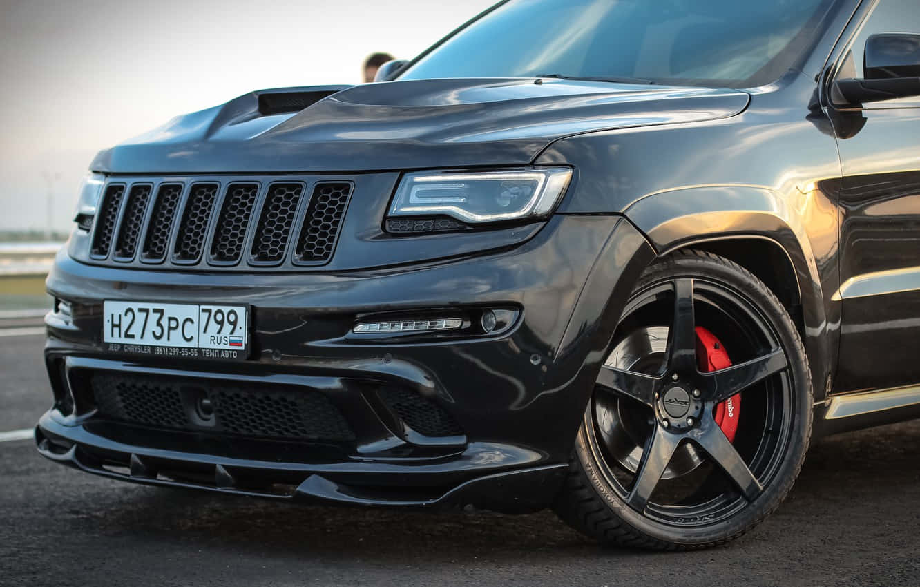 黑色Jeep Trackhawk配備紅色制動卡鉗，停在日落時分的瀝青路面上。