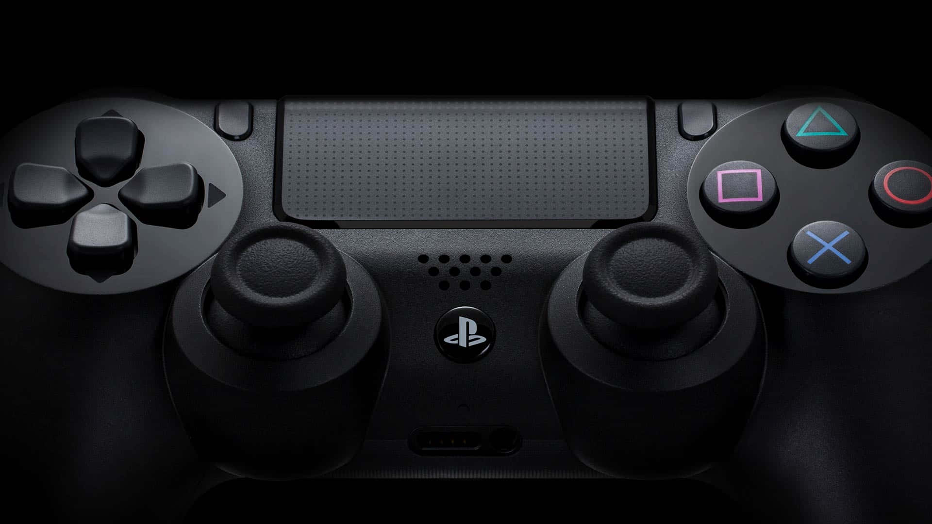 探索PlayStation的世界與更多 壁紙 — 黑色PlayStation控制器特寫，帶有發光彩色按鈕，背景黑暗。