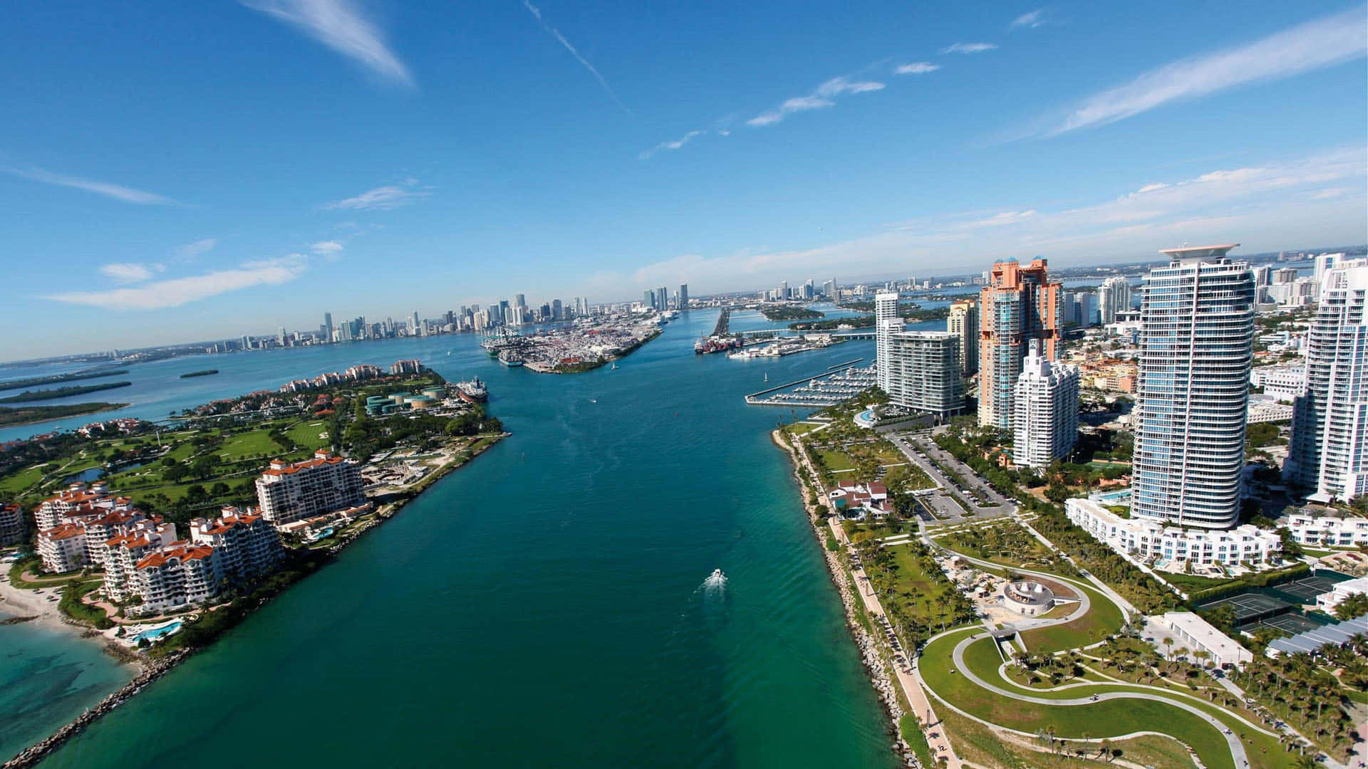 明亮藍天下，碧綠海水與現代高層建築的沿海城市天際線。
