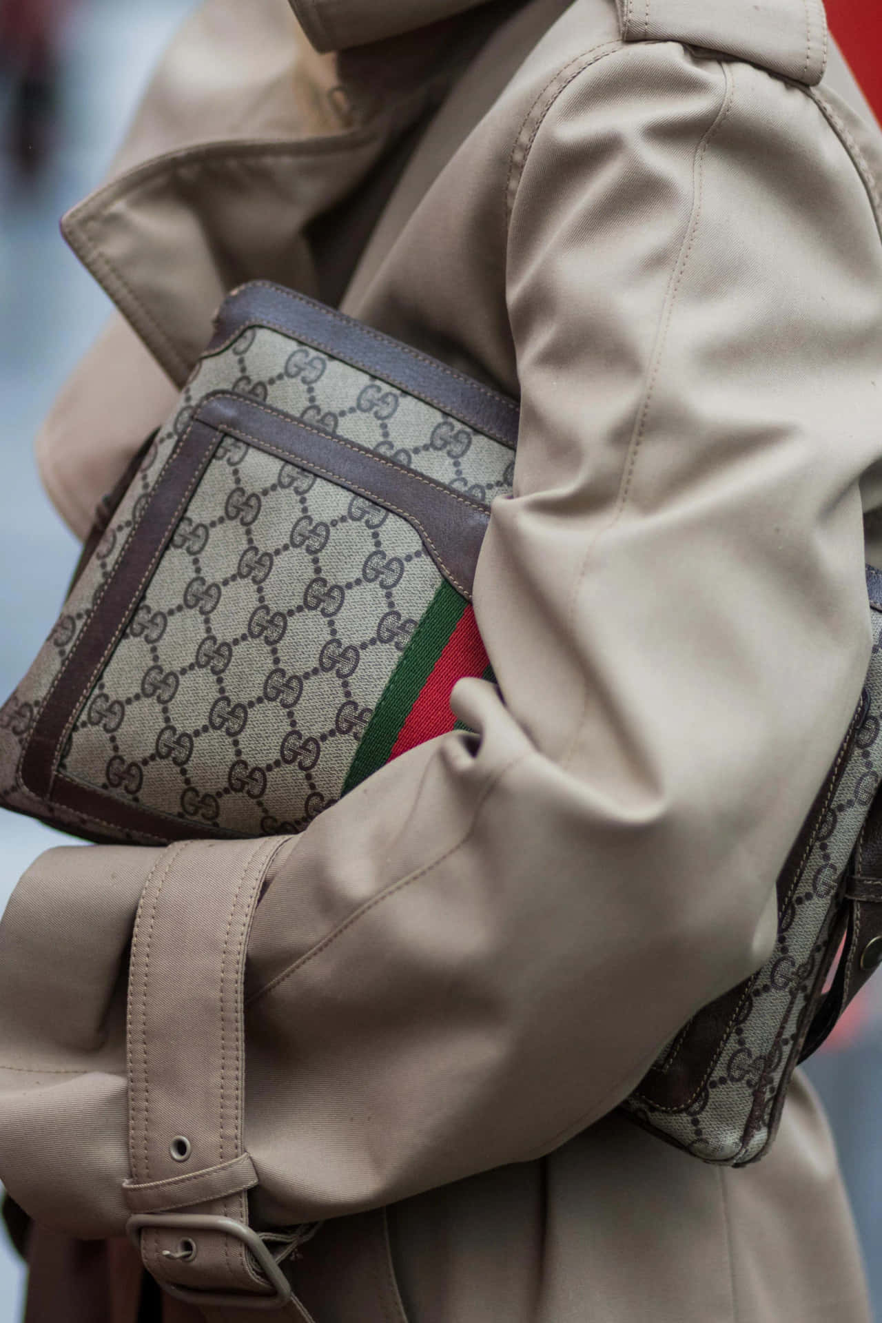 穿著米色乾濕褸的人拿著Gucci monogram肩袋。
