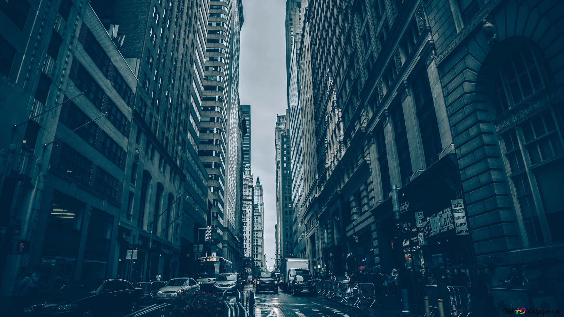 陰沉天空下，濕漉漉的城市街道兩旁高聳的建築物。