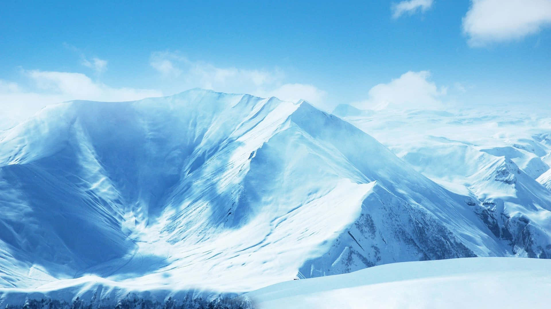 探索壯麗的雪山 壁紙 — 白雪覆蓋的山峰在清澈藍天和縷縷白雲下巍然聳立。