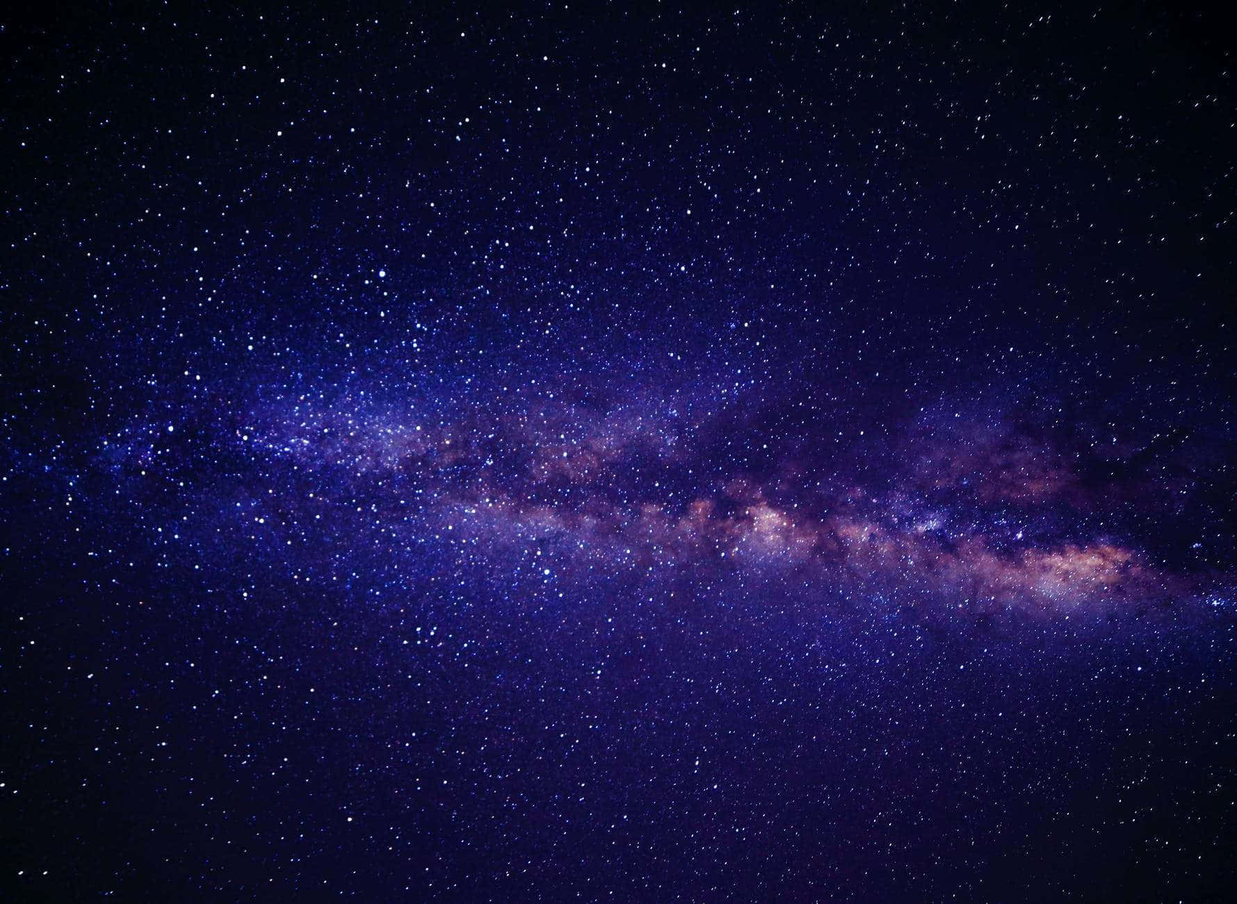 探索外太空的美麗 壁紙 — 令人嘆為觀止的銀河系景觀，在深靛藍色夜空中閃爍著紫色和粉紅色的星雲。