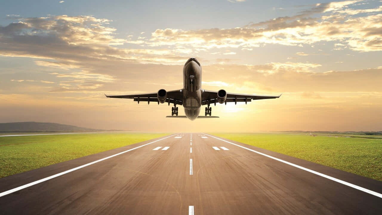 「探索天空，邁向新邊界」 壁紙 — 一架大型客機在日落時從跑道上升，金色雲彩和綠色田野延伸到地平線。