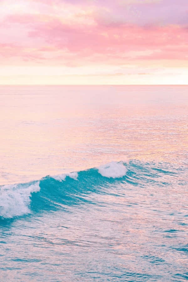 碧綠海面上的粉紅日落與捲曲的海浪