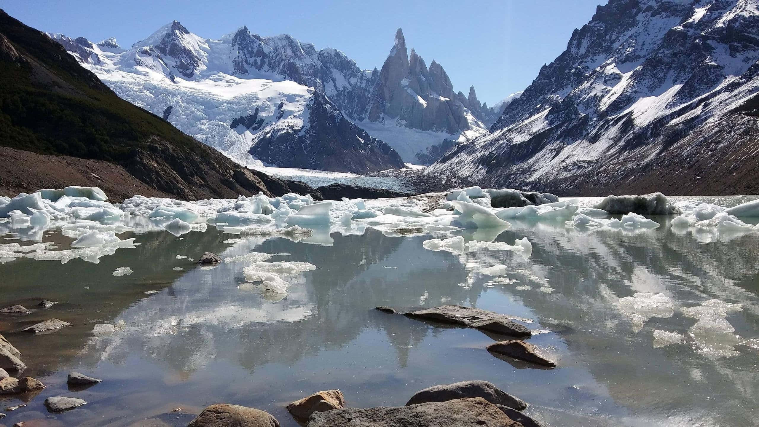 探索巴塔哥尼亞的壯麗美景 壁紙 — 寧靜的冰川湖上散落著浮冰，在清澈的藍天下映照著白雪覆蓋的山峰。