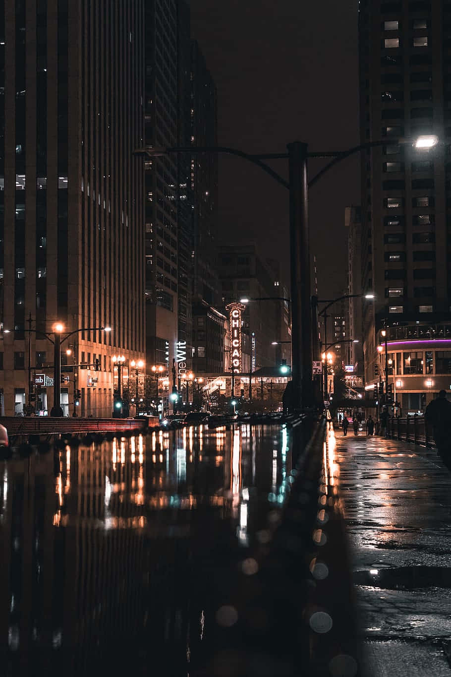 芝加哥城市街道夜景，濕漉漉的路面反射著霓虹燈光和高樓大廈。