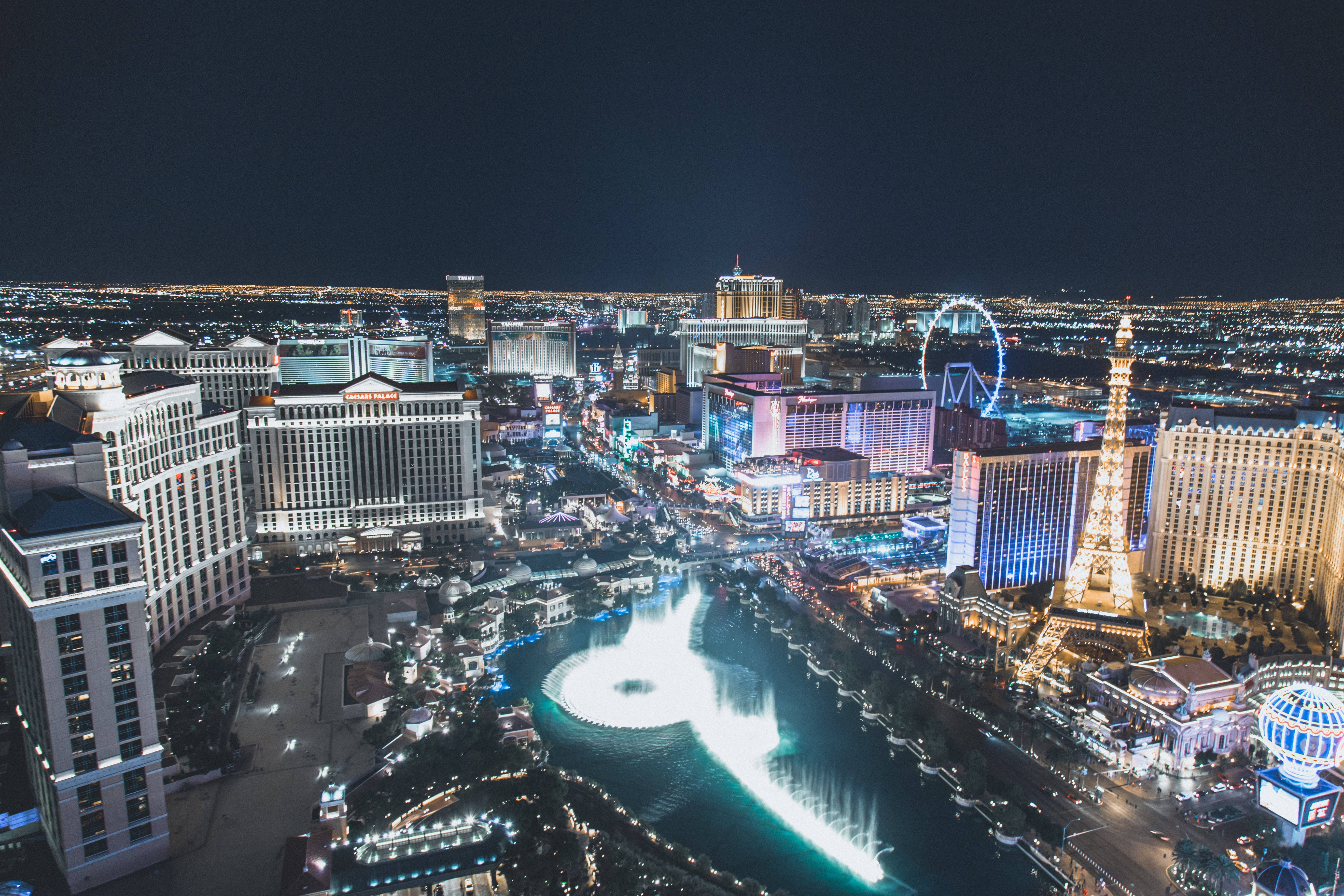 探索拉斯維加斯的夜生活 壁紙 — 拉斯維加斯令人驚嘆的夜間空中景觀，展示了燈火通明的酒店、噴泉和複製的艾菲爾鐵塔。