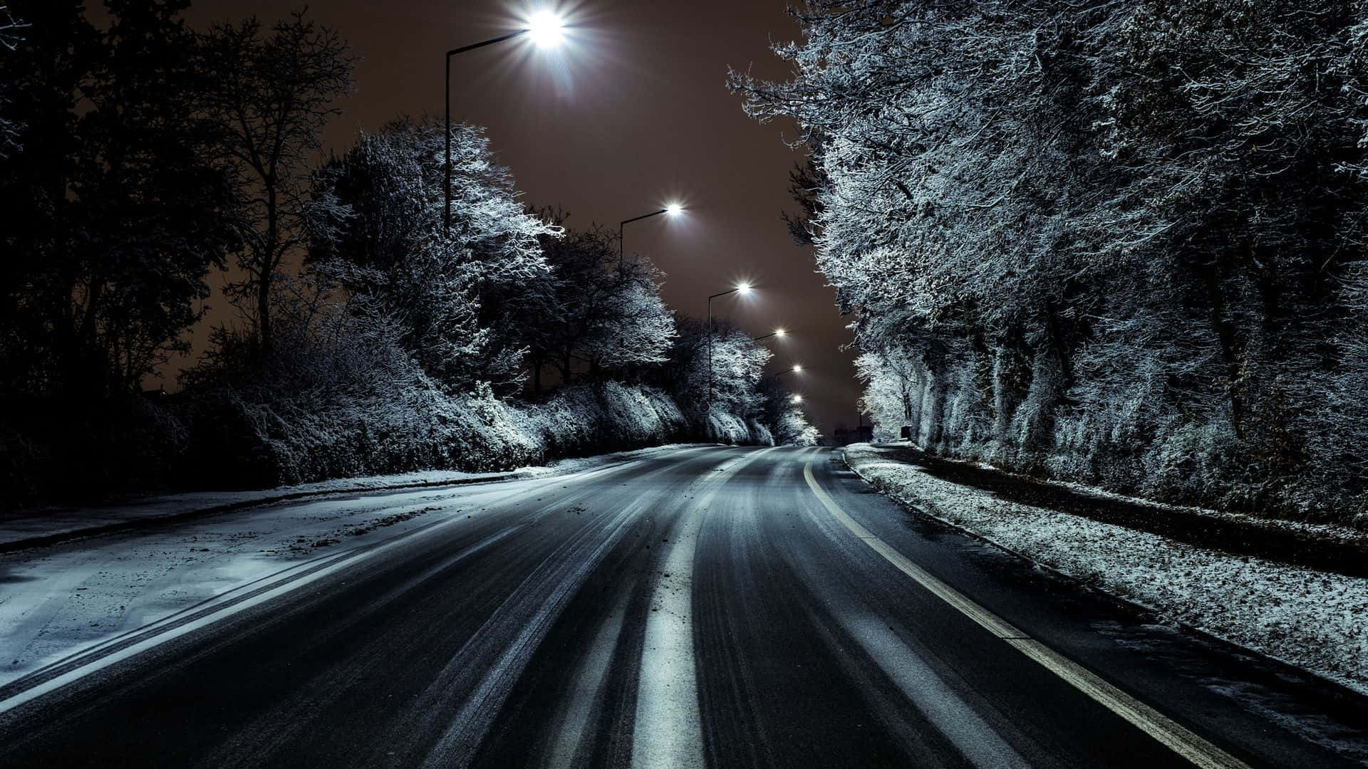 探索新公路 壁紙 — 夜晚被街燈照亮的積雪道路，兩旁是結霜的樹木。