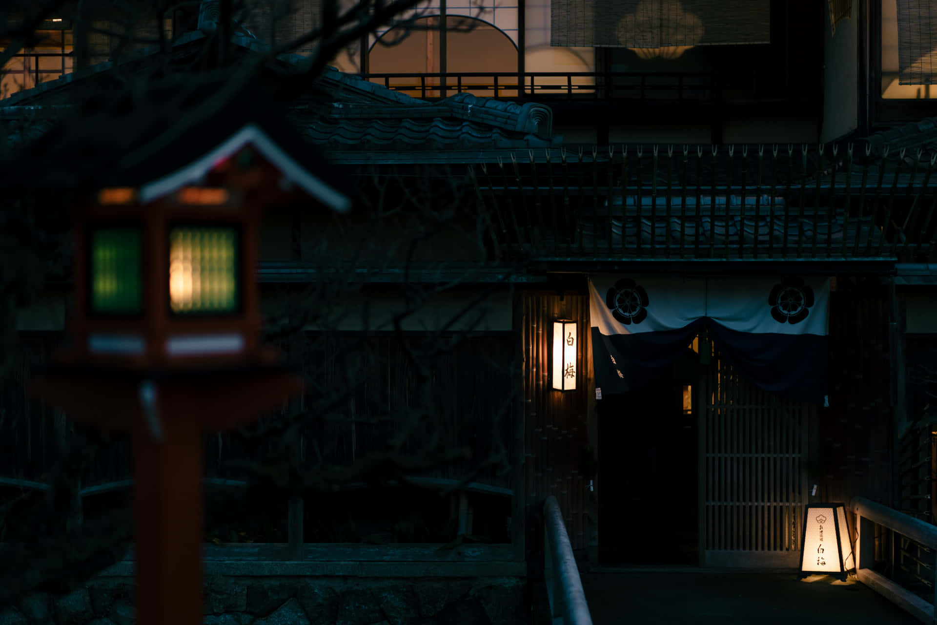 夜晚，一個發光的紅色燈籠矗立在傳統日本旅館前。
