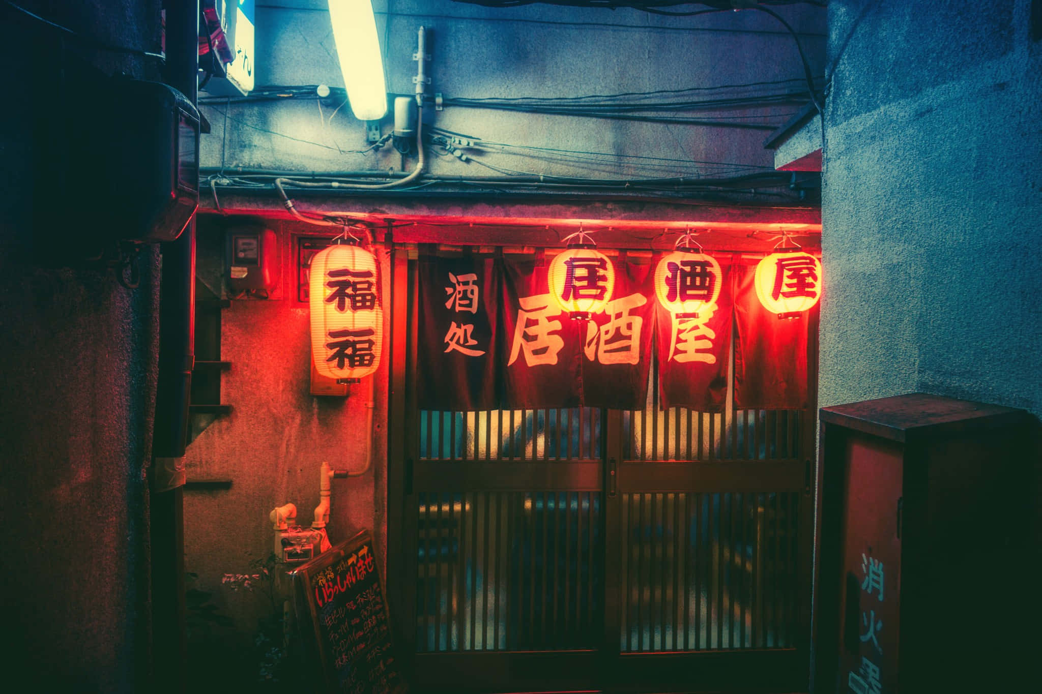 探索東京中城街道，必遇令人驚豔的霓虹色彩 壁紙 — 夜晚狹窄的小巷，被傳統日本居酒屋入口上方發光的紅色霓虹燈籠和招牌照亮。