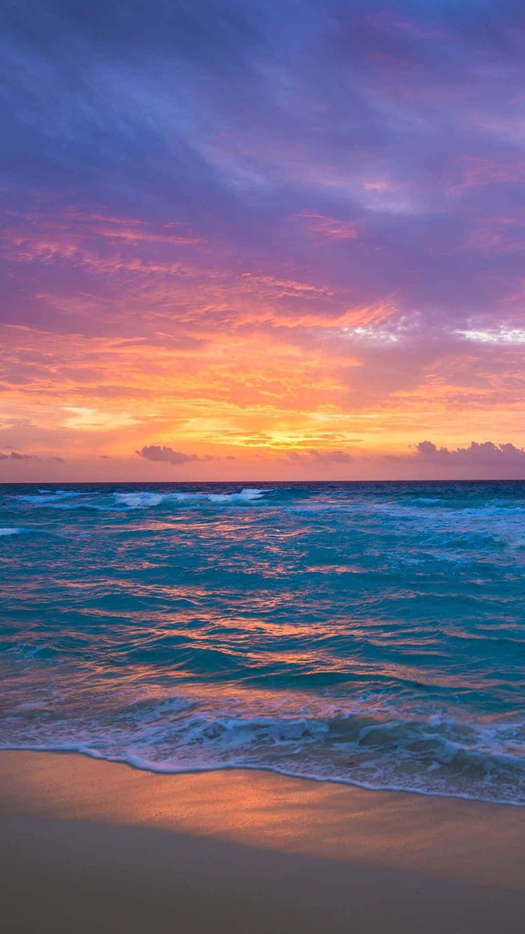 夕陽映照海洋，天空色彩繽紛，沙灘上輕柔的海浪