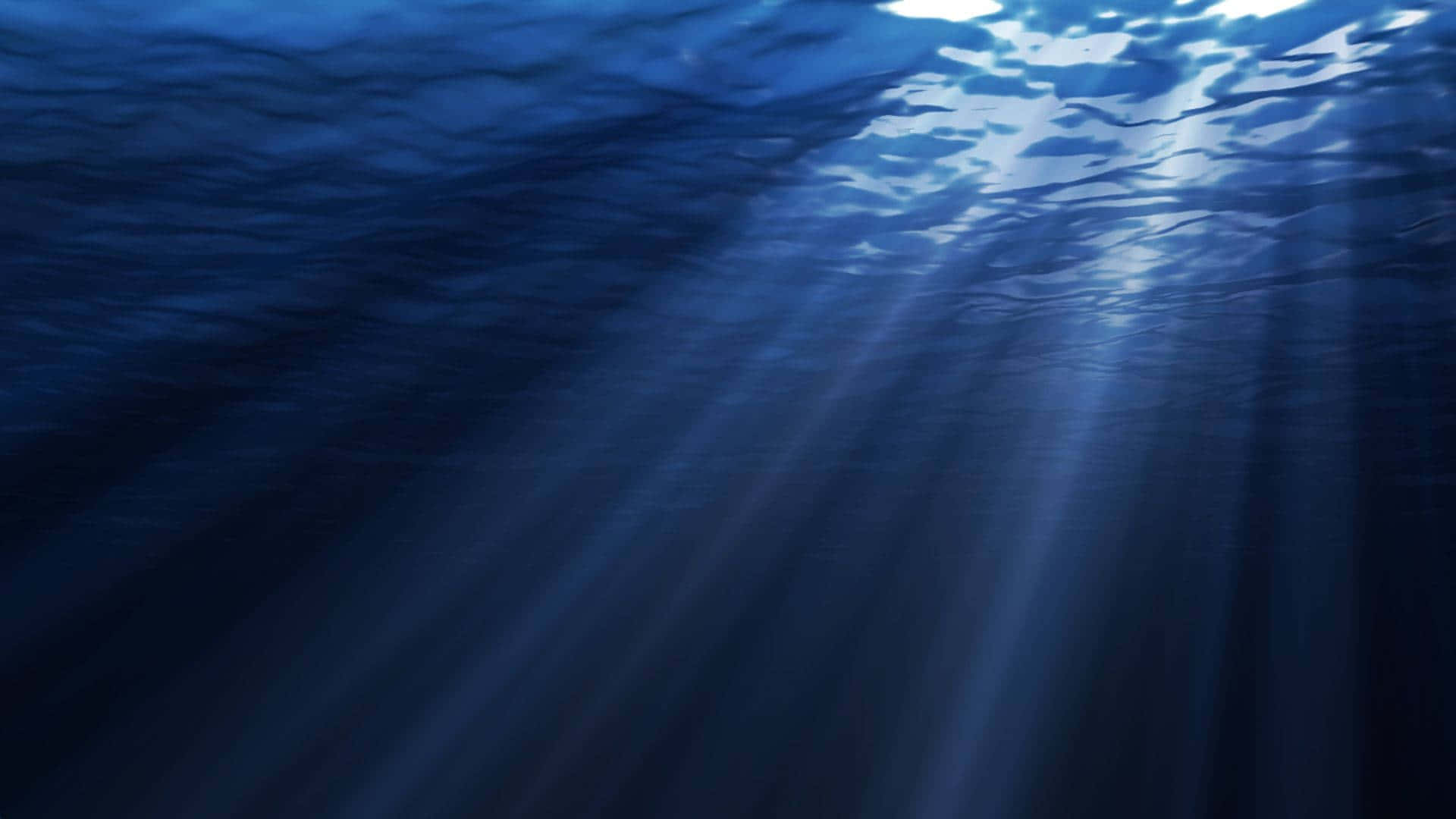 探索海洋隱藏的未知深處 壁紙 — 陽光穿透深藍色海浪，營造出寧靜的水下光芒。