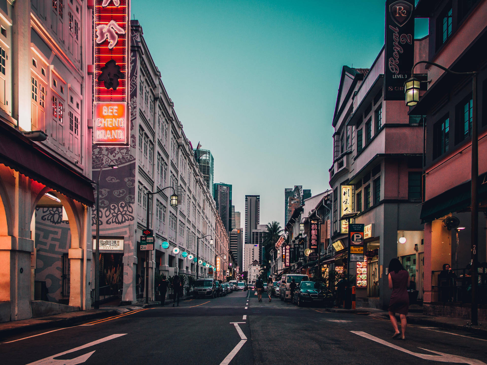黃昏城市街道，霓虹燈招牌和殖民建築通往現代摩天大樓。