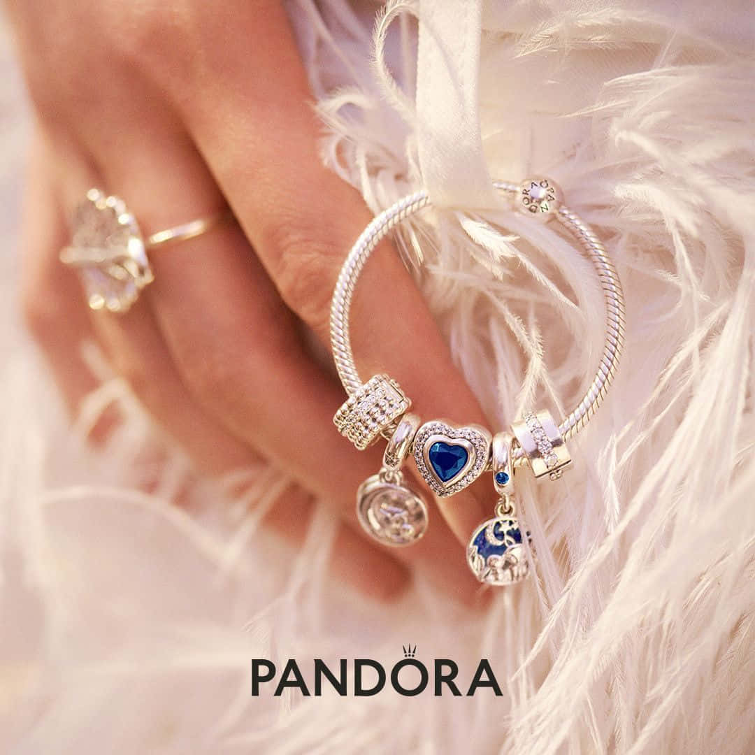 戴著Pandora吊飾手鏈和戒指的手放在白色羽毛上。