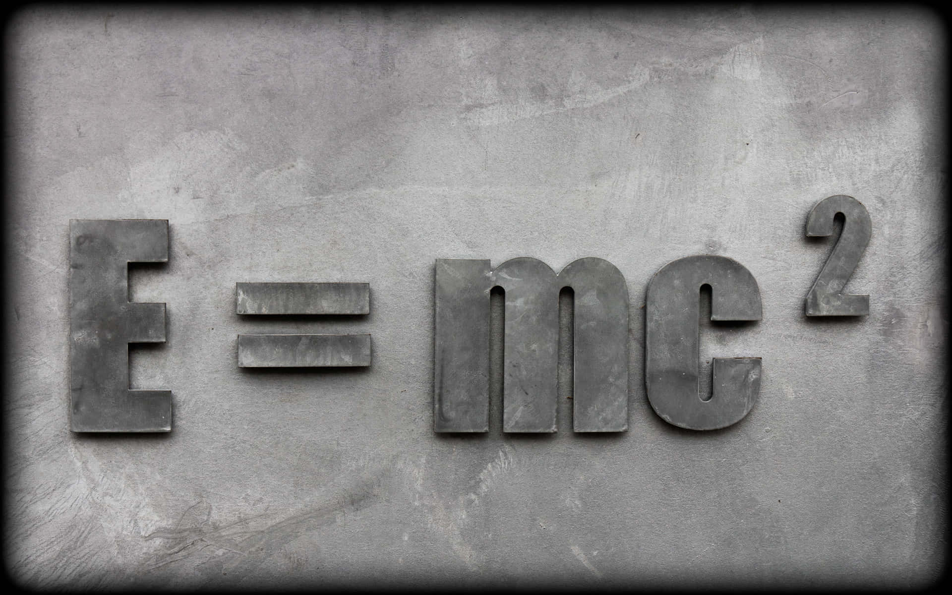 混凝土牆上凸起的金屬字母E=mc²公式。
