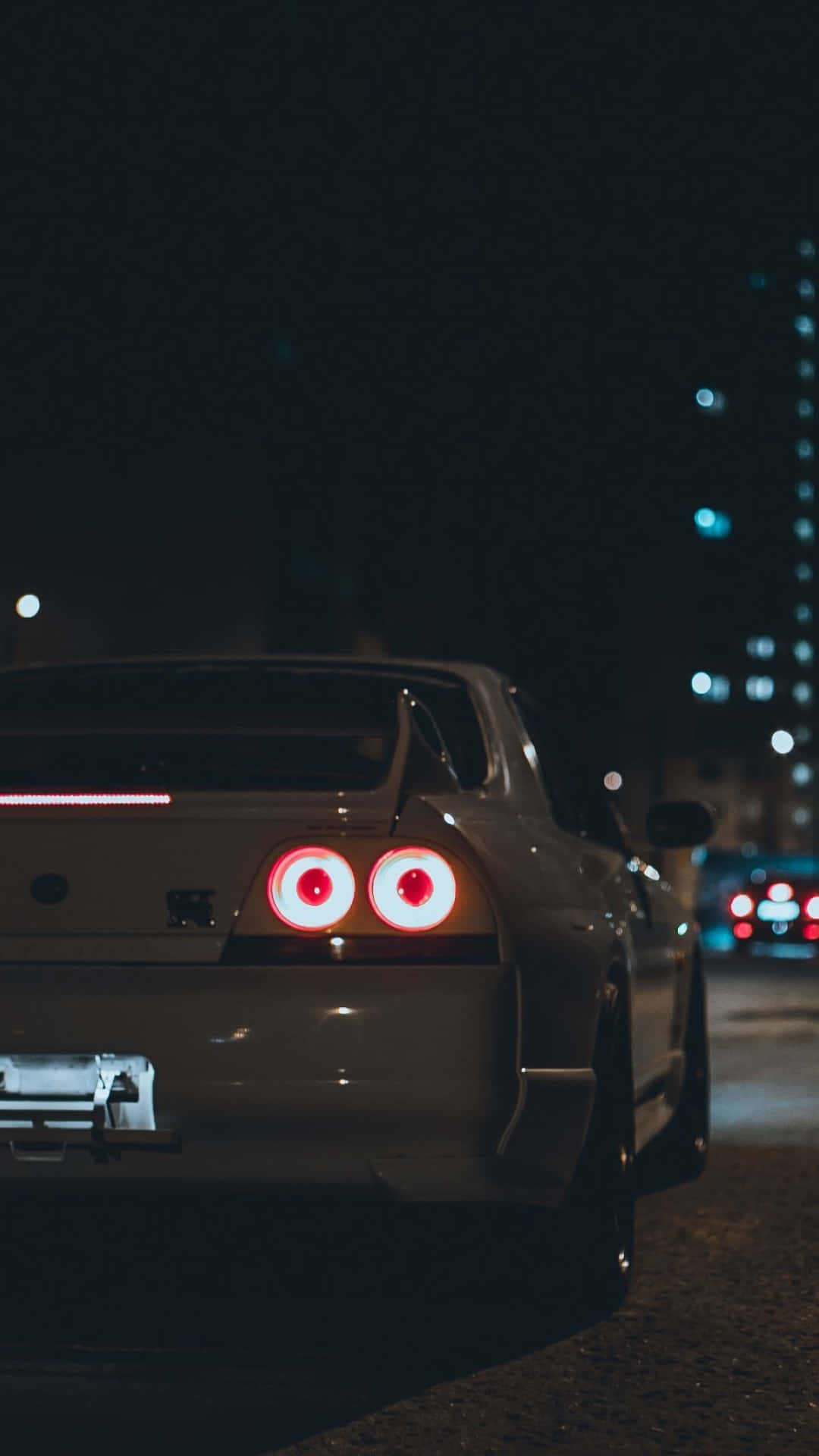 銀色跑車，紅色尾燈，停在夜晚的城市街道上。