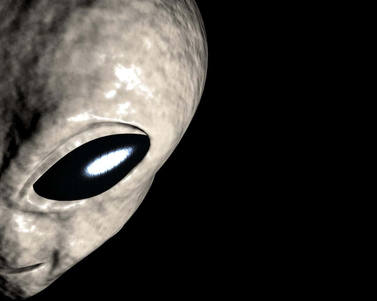 探索神秘外星的秘密 壁紙 — 灰色外星人面孔特寫，有一隻發光的大眼睛，背景是黑色虛空。