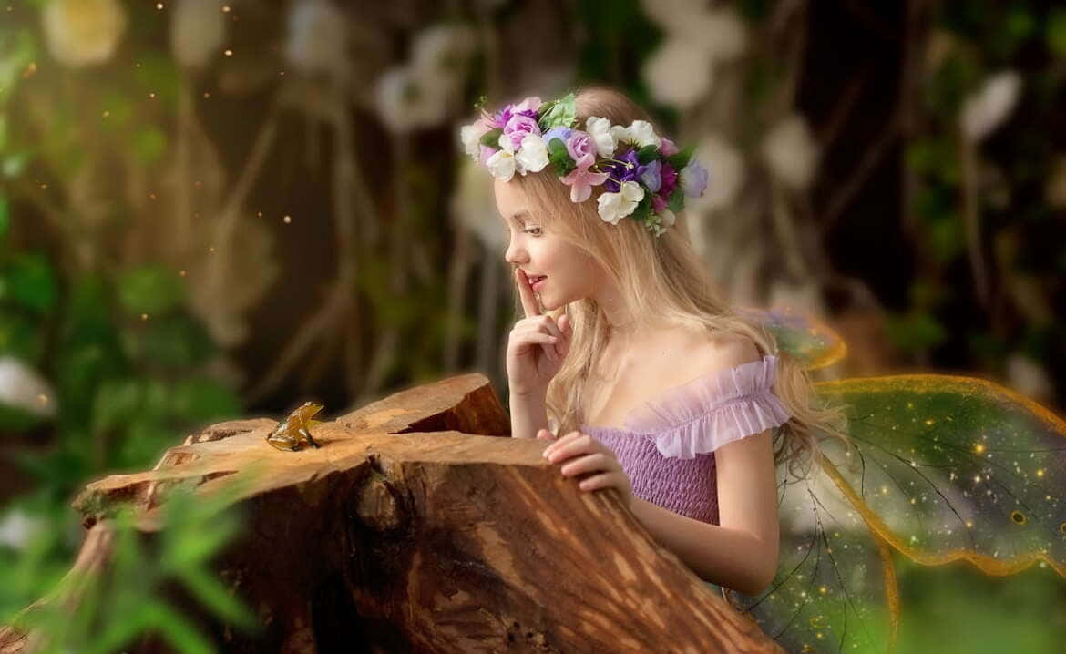 戴花冠和發光翅膀的仙女女孩在森林裡對青蛙低語。