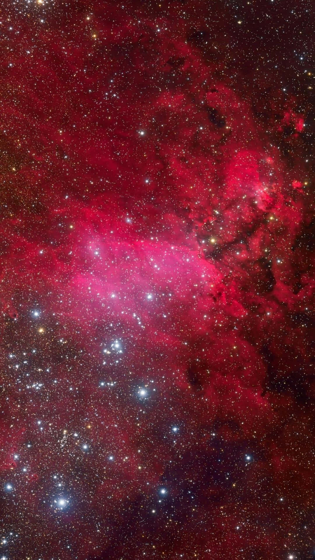 深空中充滿閃爍星星的鮮豔紅色星雲。