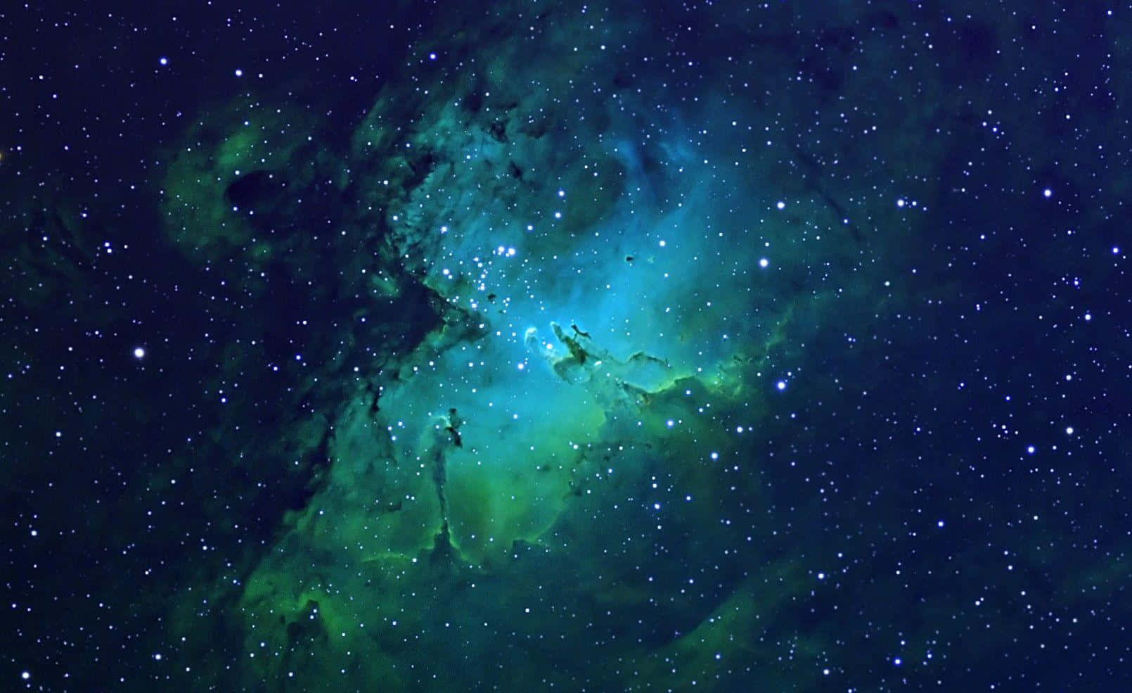 在廣闊的夜空中，一個充滿星星的發光綠色和藍色星雲。