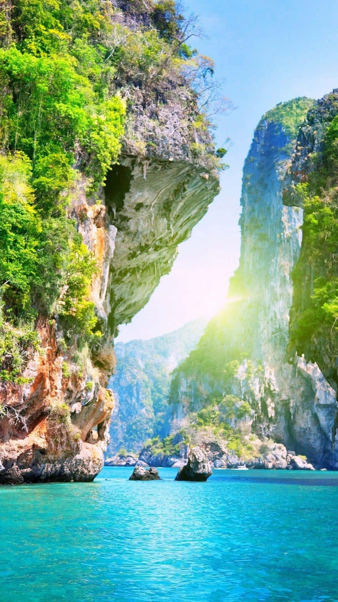 陽光穿過岩石拱門，照射在碧綠海水和綠色懸崖上。