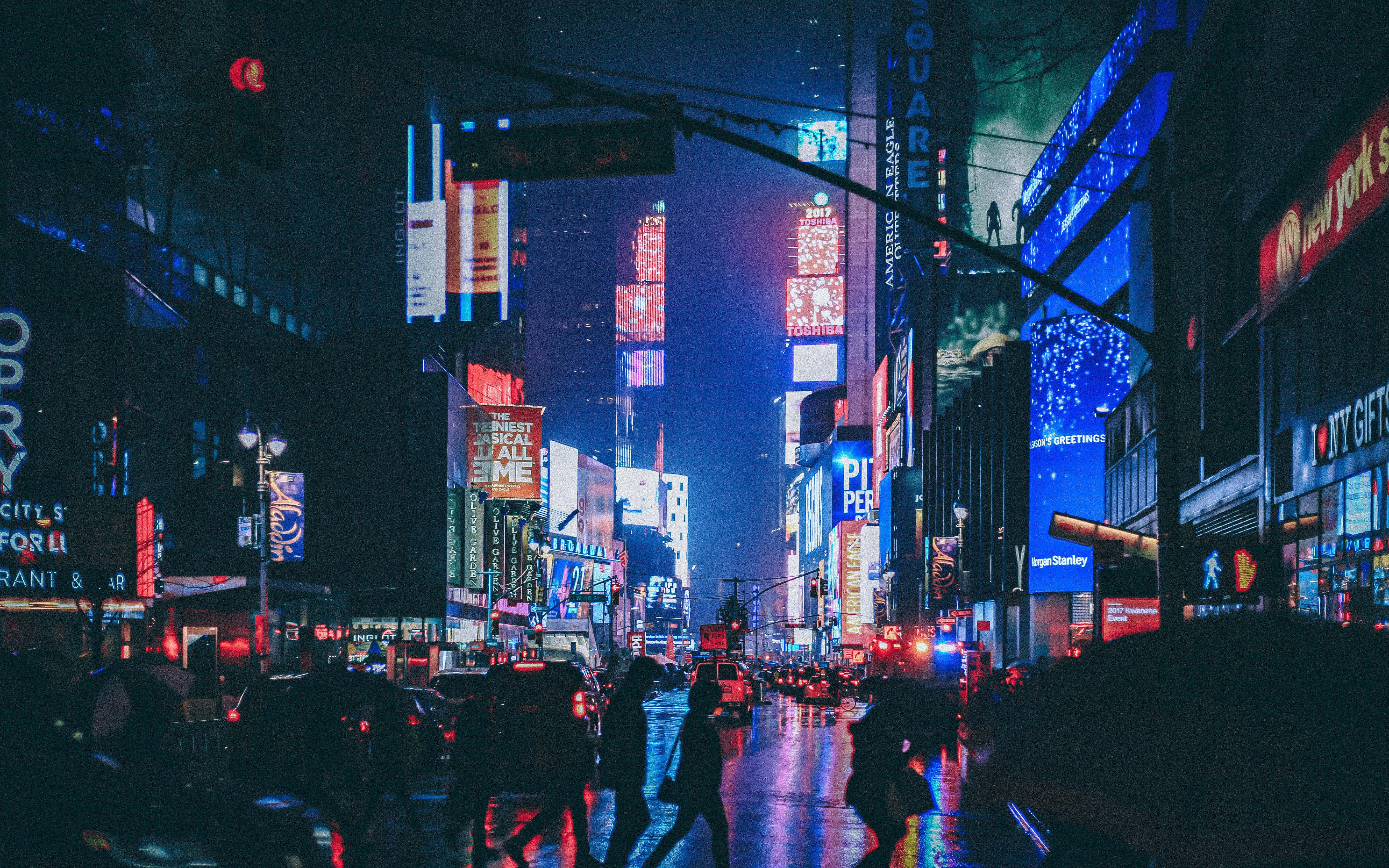探索霓虹都市——一場視覺盛宴 壁紙 — 時代廣場的雨夜，發光的霓虹招牌映照在濕漉漉的人行道上，模糊的行人穿過馬路。