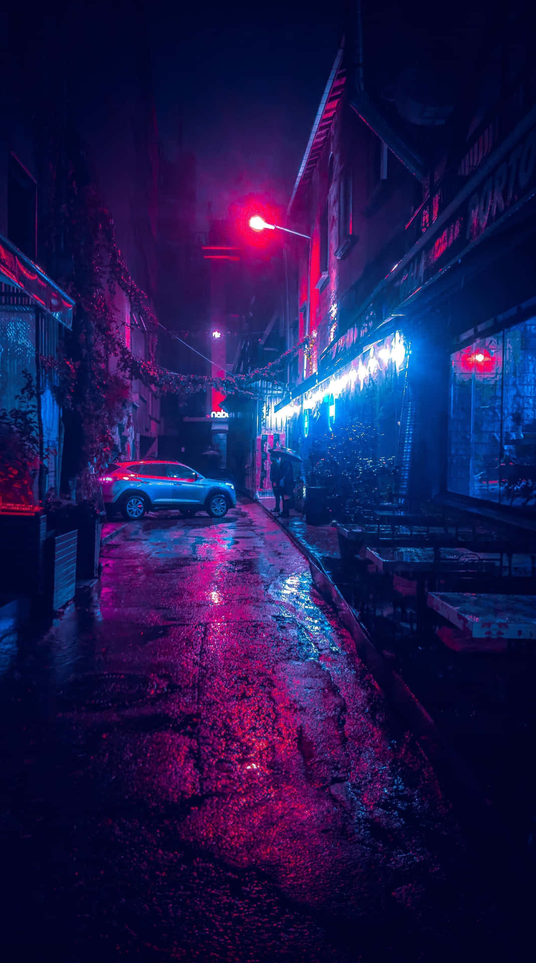 雨濕的都市小巷在夜晚閃爍著紅色和藍色的霓虹燈光。