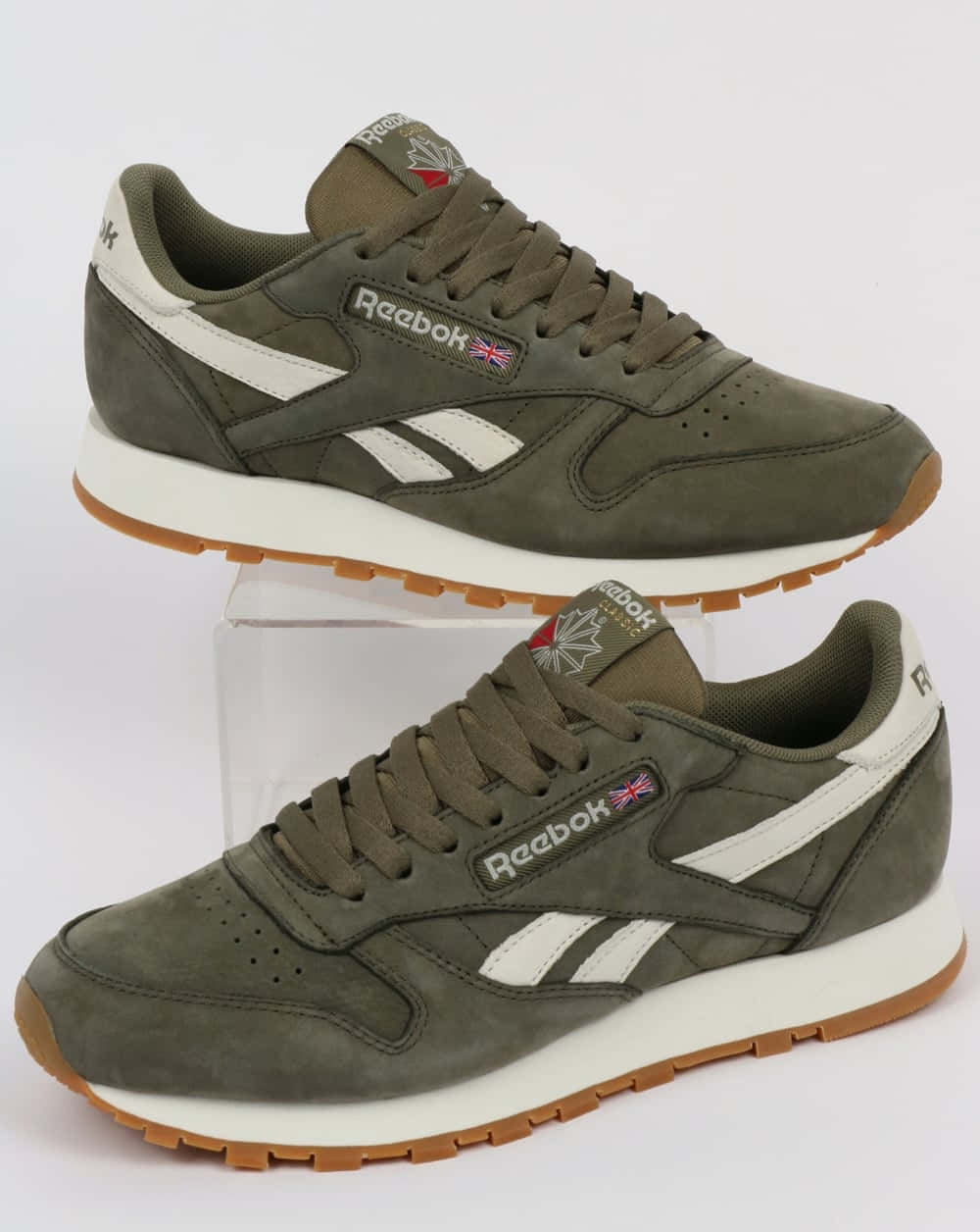 提升你的健身表現，選擇Reebok 壁紙 — 兩雙橄欖綠色Reebok運動鞋，帶有白色條紋和膠底，展示在透明支架上，背景為純白色。