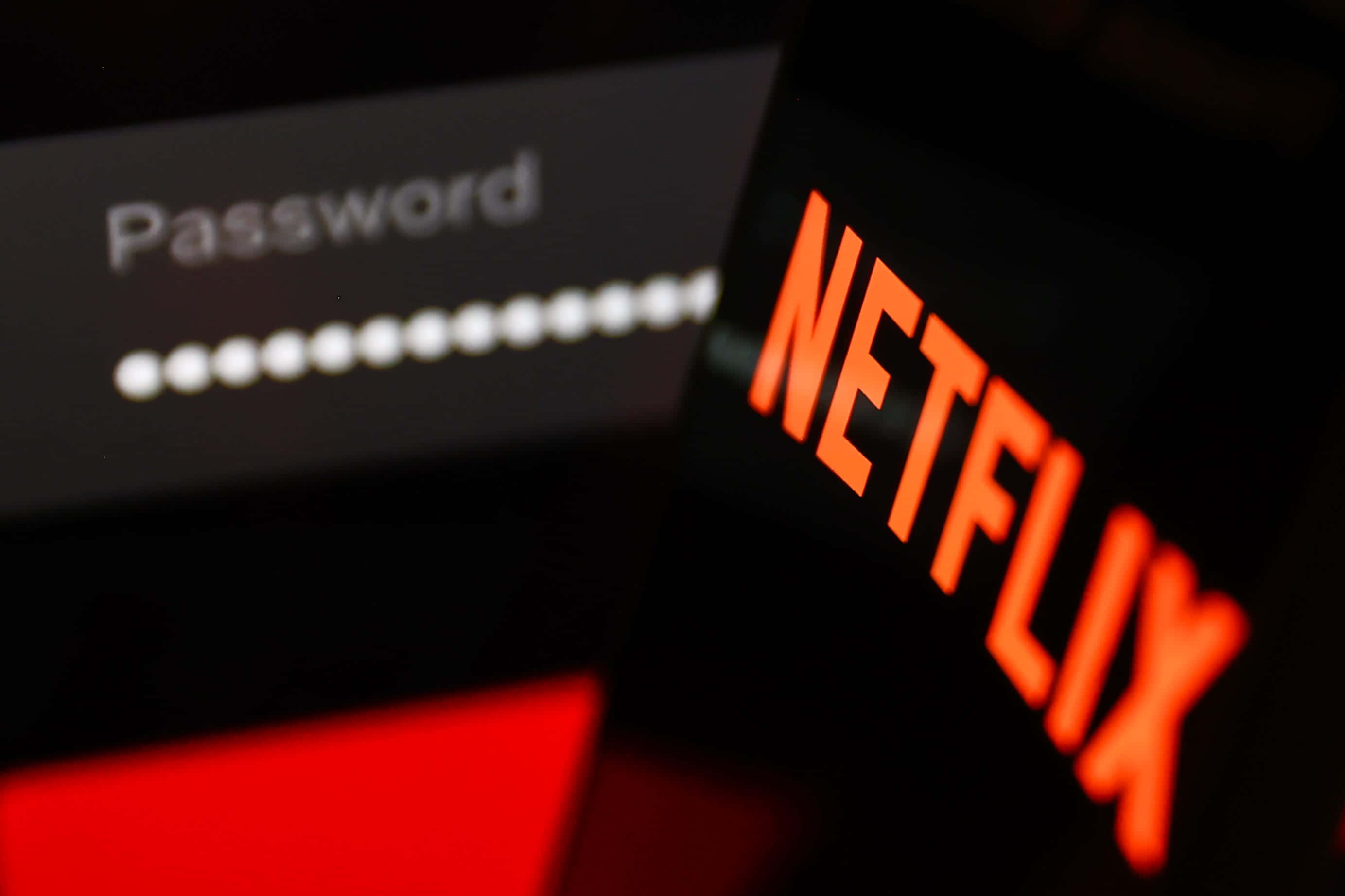 手機螢幕顯示Netflix登入，帶有密碼欄位和發光的橙色標誌。