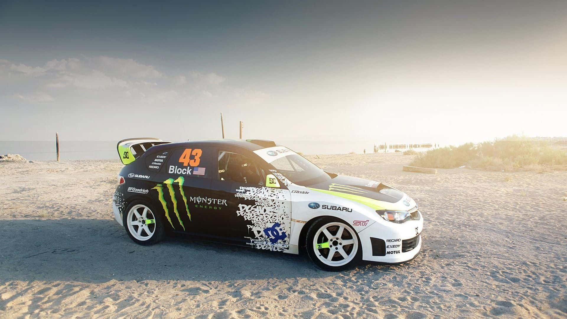 帶有Monster Energy品牌的Subaru拉力賽車，在日落時分停泊在沙灘上。