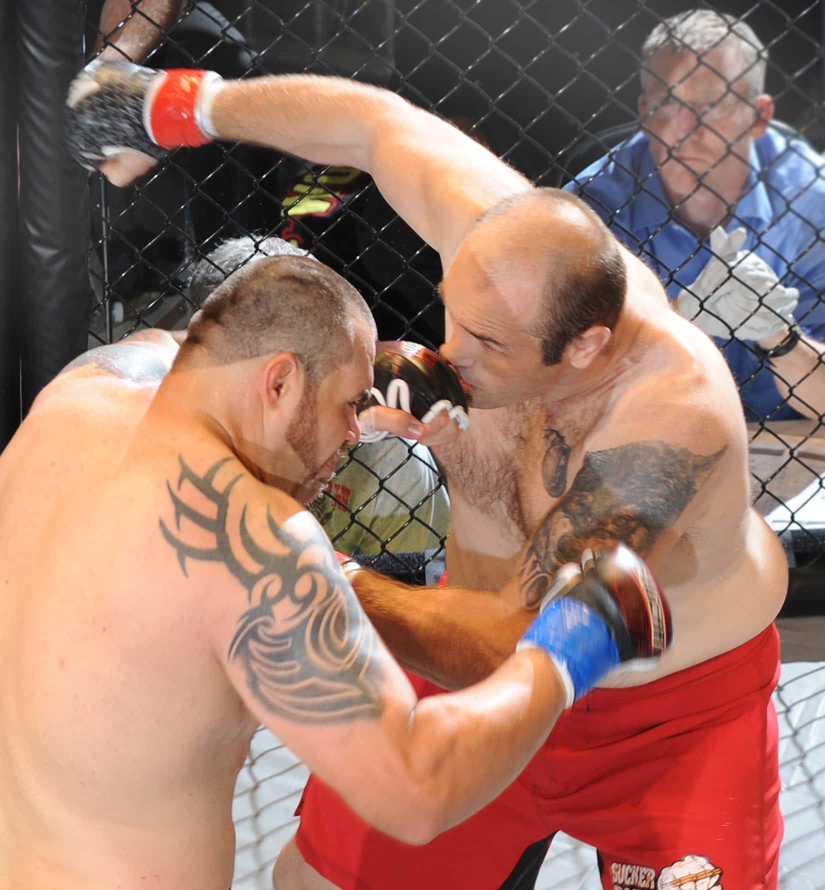 提姆·西爾維亞前UFC綜合格鬥選手 壁紙 — 兩名紋身拳手在籠中交鋒，其中一人向對手面部猛烈出拳。
